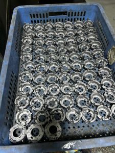 Large quantity of identical die casting metal parts neatly arranged in a blue industrial storage crate