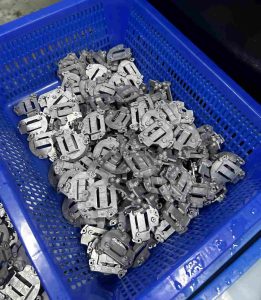 Pile of finished die casting metal components in a blue plastic industrial basket